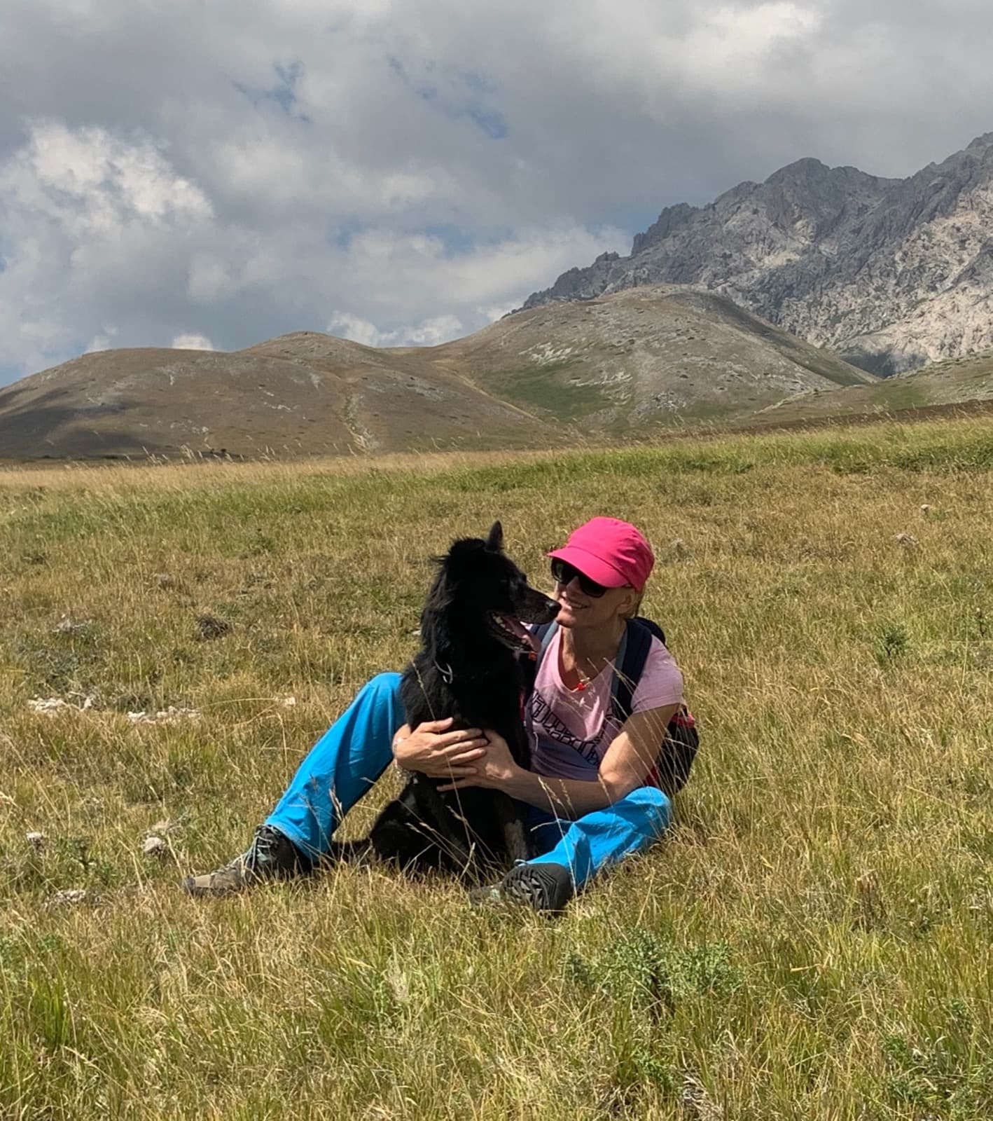 Sabrina Prioli seduta nell'erba a Campo Imperatore, in Abruzzo, con il suo cane